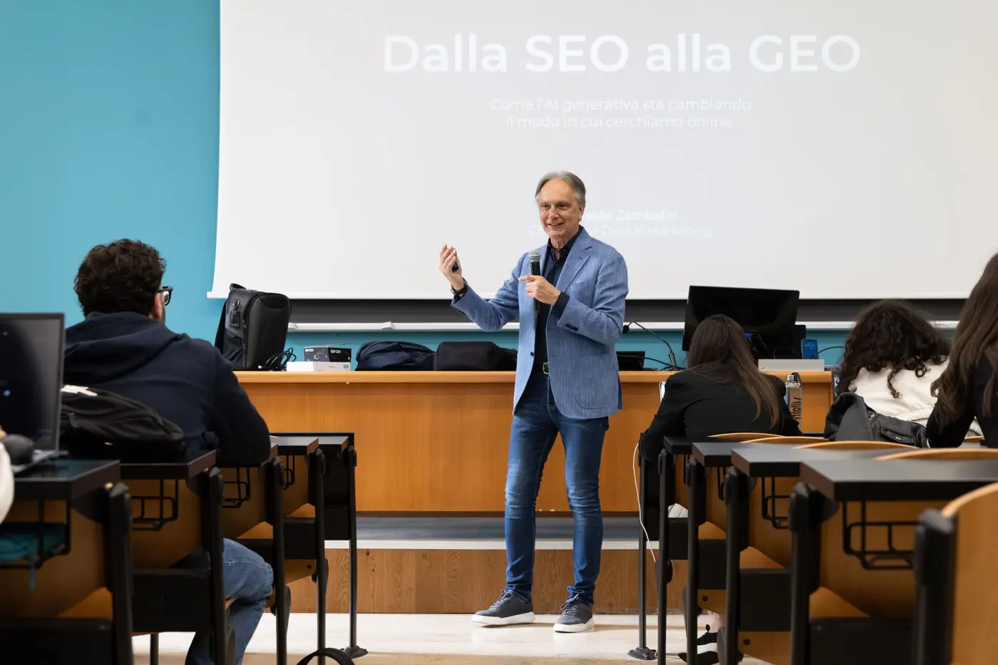Rinaldo Zambello speaking in class in front of the slide From SEO to GEO